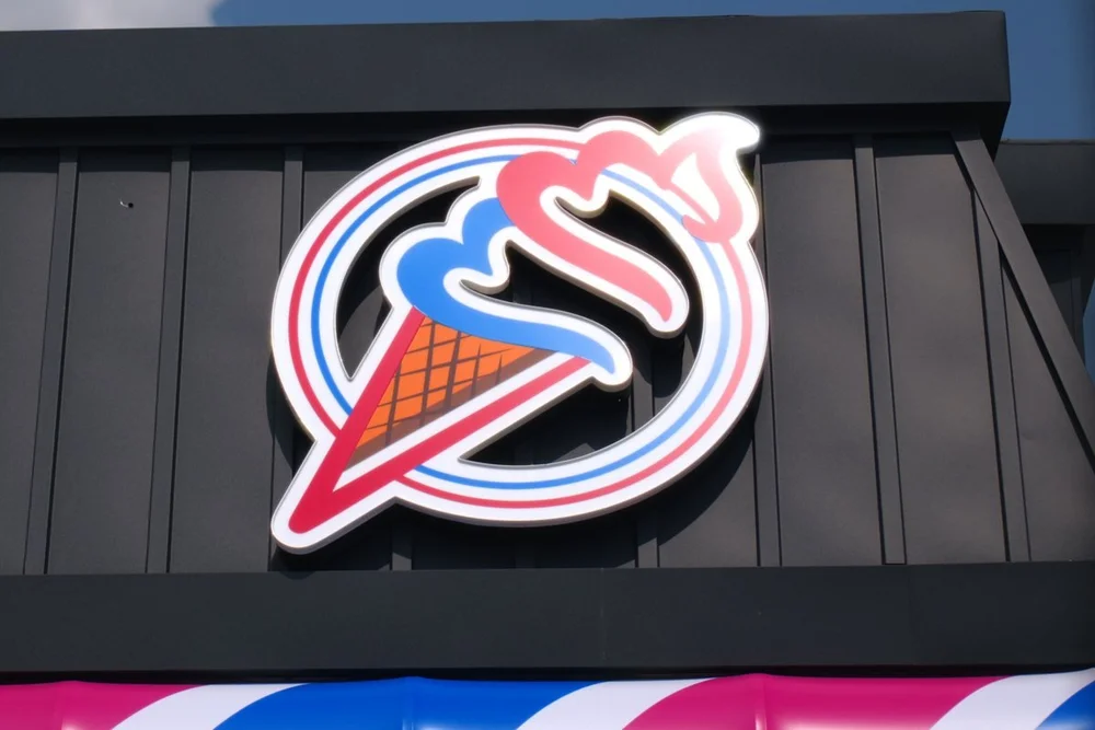 Merla-Mae cone logo sign above the striped awning at Merla-Mae Ice Cream in London, Ontario