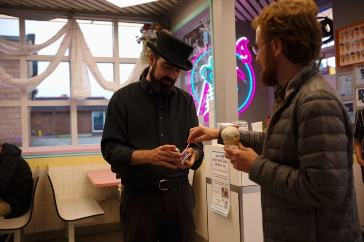 Guest holding an ice cream cone while the magician performs close-up card magic at Merla-Mae Ice Cream