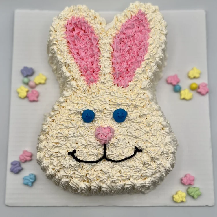 Bunny-shaped ice cream cake with pink piped ears, blue eyes and a smile, surrounded by pastel candy flowers, at Merla-Mae Ice Cream in London, Ontario