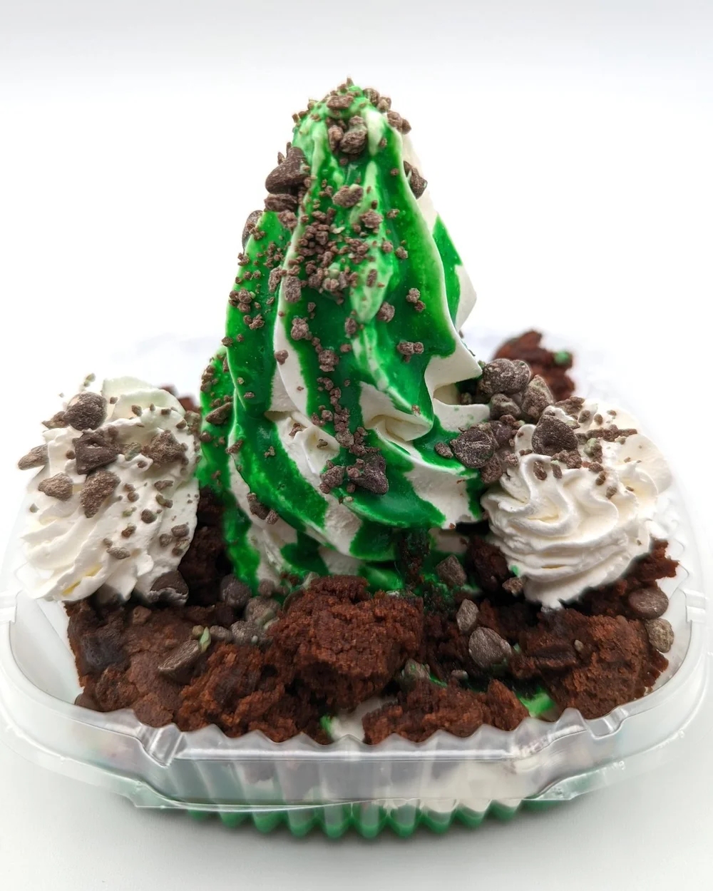 Green and white swirled soft-serve on brownie pieces with whipped cream and chocolate chips in a clear sundae container at Merla-Mae Ice Cream in London, Ontario