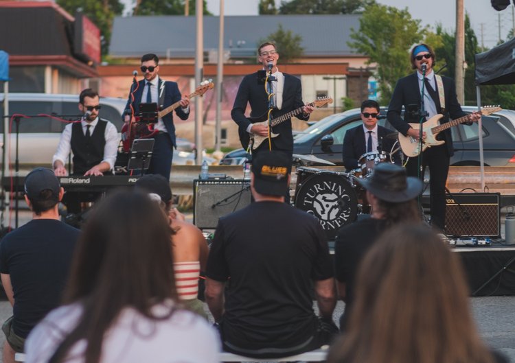 Seated crowd watching Turning Corners perform at National Ice Cream Day 2024, Merla-Mae Ice Cream in London, Ontario