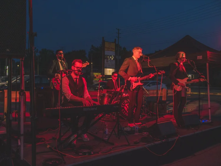 Turning Corners playing under red stage lights after dark at National Ice Cream Day 2024, Merla-Mae Ice Cream in London, Ontario