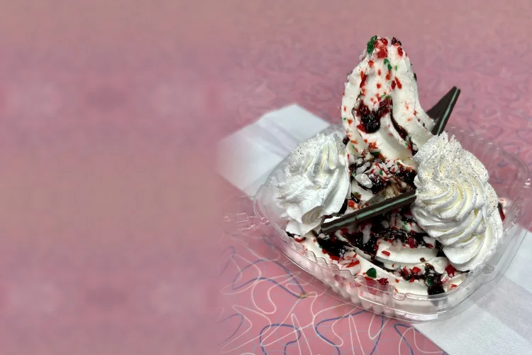 Chocolate peppermint sundae with fudge, crushed candy cane, whipped cream and mint chocolate thins on a pink boomerang tabletop, at Merla-Mae Ice Cream in London, Ontario
