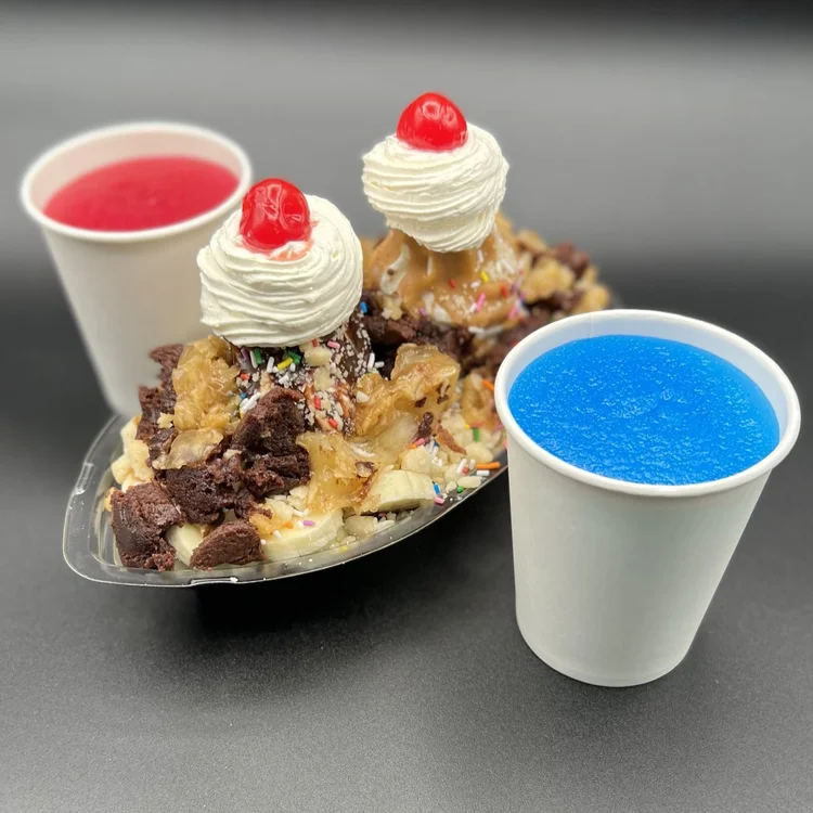 Red and blue slushies beside a loaded sundae with whipped cream and cherries at Merla-Mae Ice Cream in London, Ontario