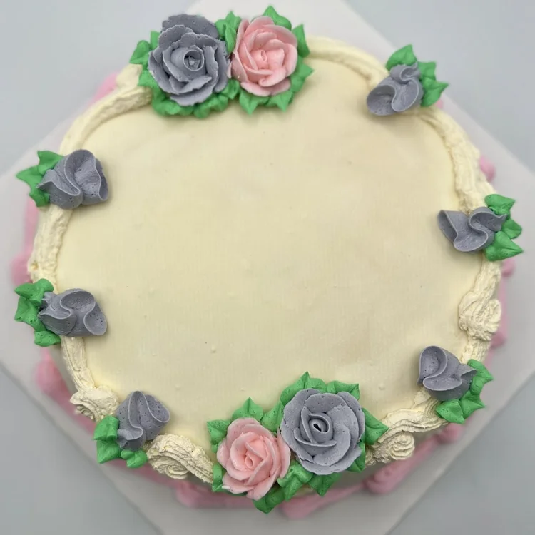 Round ice cream cake decorated with piped pink and lavender roses and green leaves at Merla-Mae Ice Cream in London, Ontario