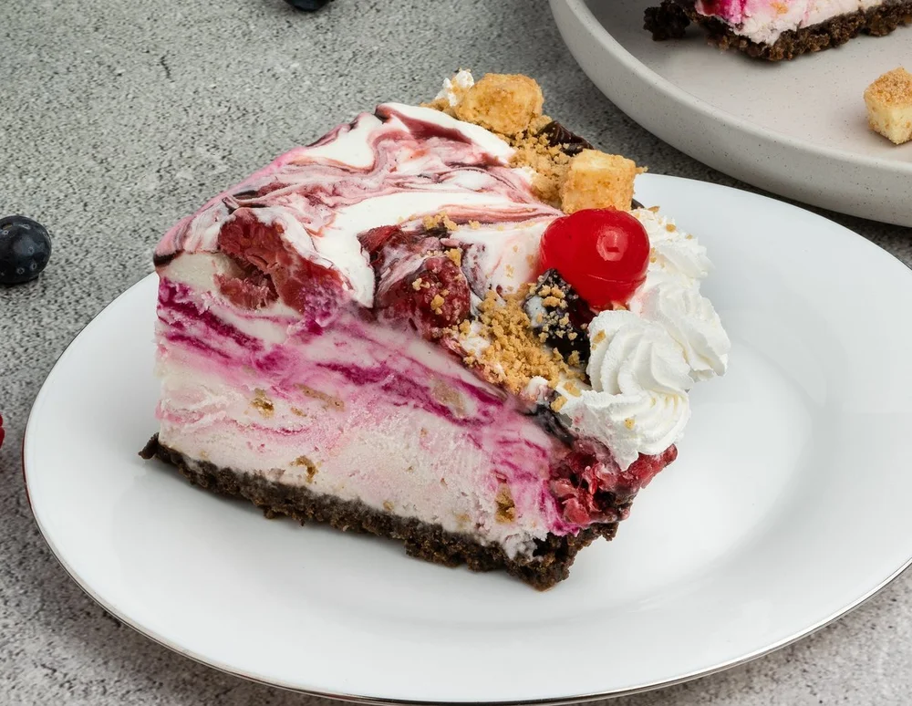 Slice of Very Berry Cheesecake ice cream pie swirled with berries and topped with whipped cream at Merla-Mae Ice Cream in London, Ontario