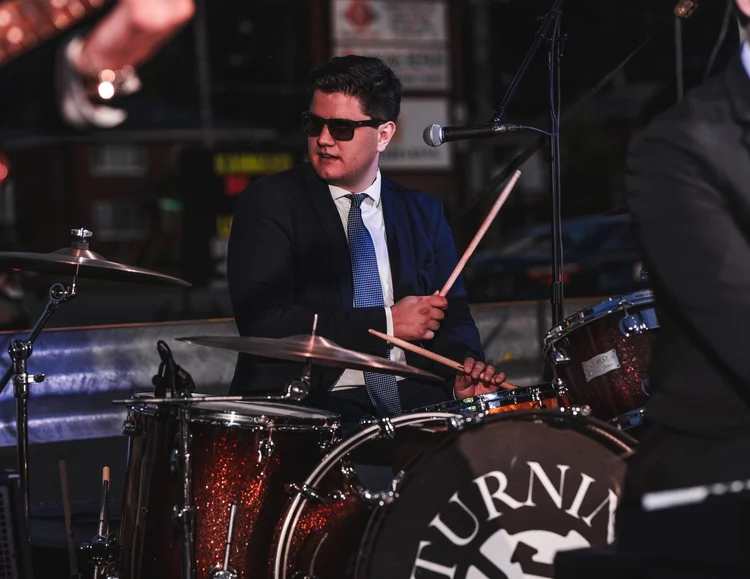 Turning Corners' drummer playing after dark at National Ice Cream Day 2025, Merla-Mae Ice Cream in London, Ontario