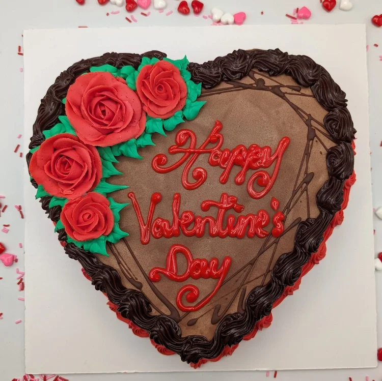 Heart-shaped ice cream cake with chocolate icing, piped with Happy Valentine&rsquo;s Day in red, with red icing roses and a dark chocolate border, at Merla-Mae Ice Cream in London, Ontario
