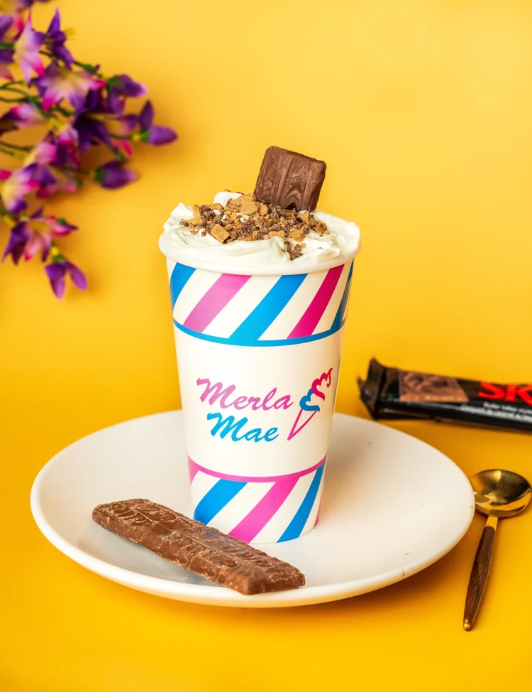 Skor Cream Shake Flurry topped with toffee pieces and a Skor bar in a striped cup at Merla-Mae Ice Cream in London, Ontario