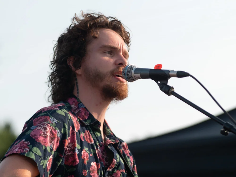 Tyrone Traher singing into the mic during his set at National Ice Cream Day 2024, Merla-Mae Ice Cream in London, Ontario