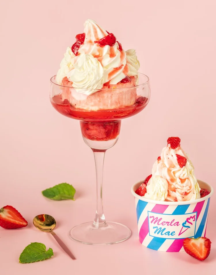 Strawberry sundae topped with whipped cream and fresh strawberries, with a second served in a tall glass at Merla-Mae Ice Cream in London, Ontario