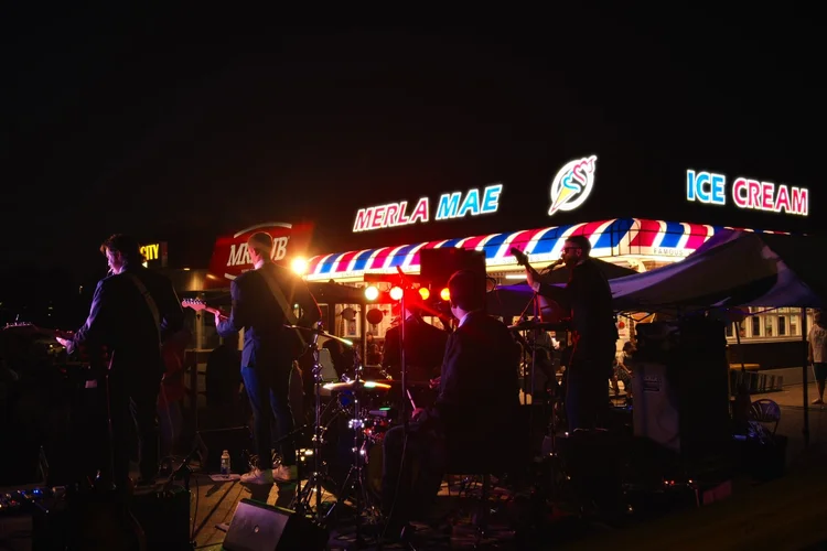 Turning Corners performing at night outside the Merla-Mae ice cream stand, National Ice Cream Day 2026