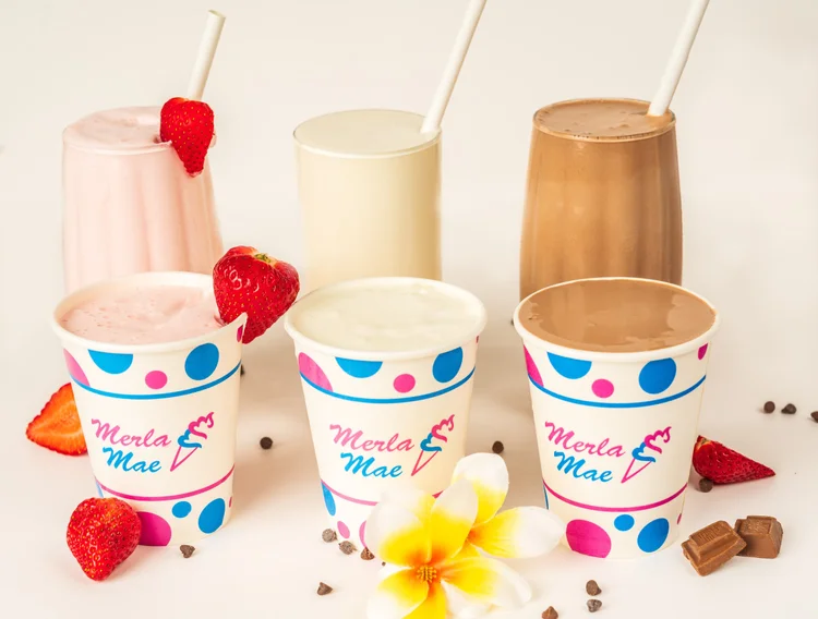 Strawberry, vanilla and chocolate milkshakes in tall glasses and polka-dot Merla-Mae cups with fresh strawberries, chocolate pieces and a white flower at Merla-Mae Ice Cream in London, Ontario