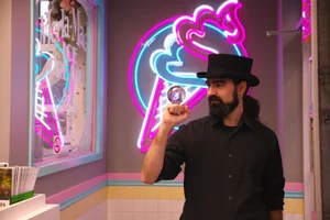 Magician in a top hat holding up a crystal ball under the neon cone sign during Magician Weekend at Merla-Mae Ice Cream in London, Ontario