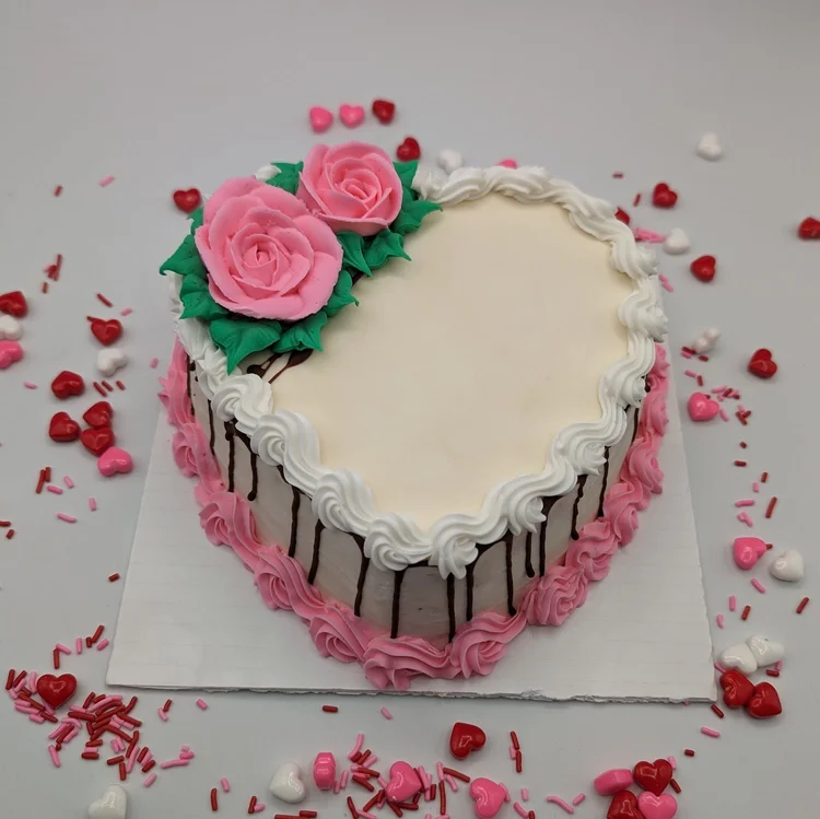 Heart-shaped ice cream cake with two pink icing roses, white and pink piped borders and chocolate drips down the sides at Merla-Mae Ice Cream in London, Ontario