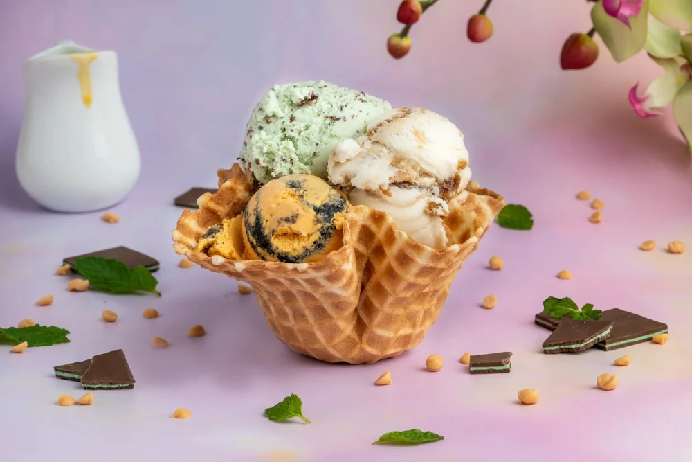 Three scoops of hard ice cream in a waffle dish with chocolate pieces and mint leaves at Merla-Mae Ice Cream in London, Ontario