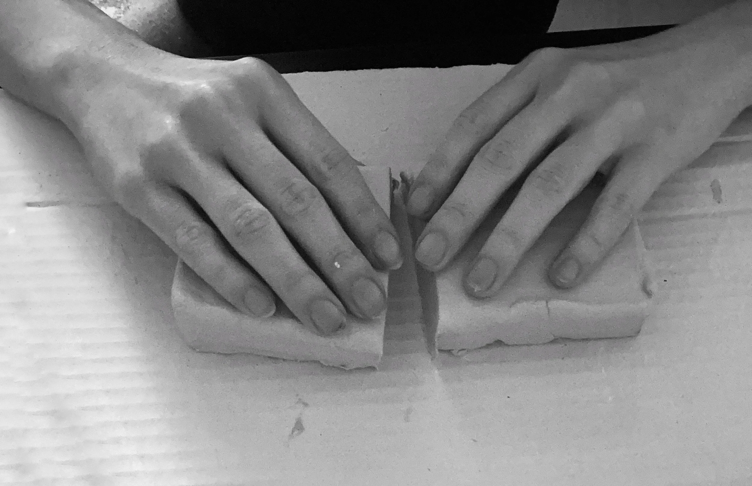 Hands folding a piece of paper over a table.