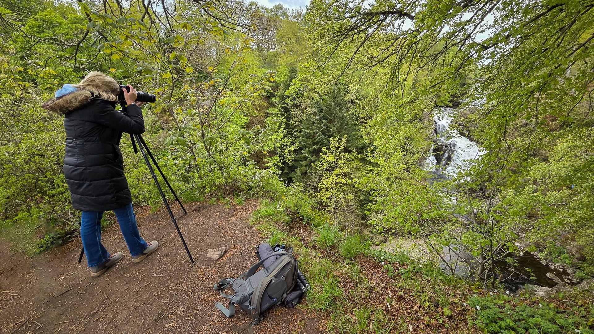 Photographer using a tripod at Reekie Linn waterfall during a beginner photography workshop in Angus, Scotland