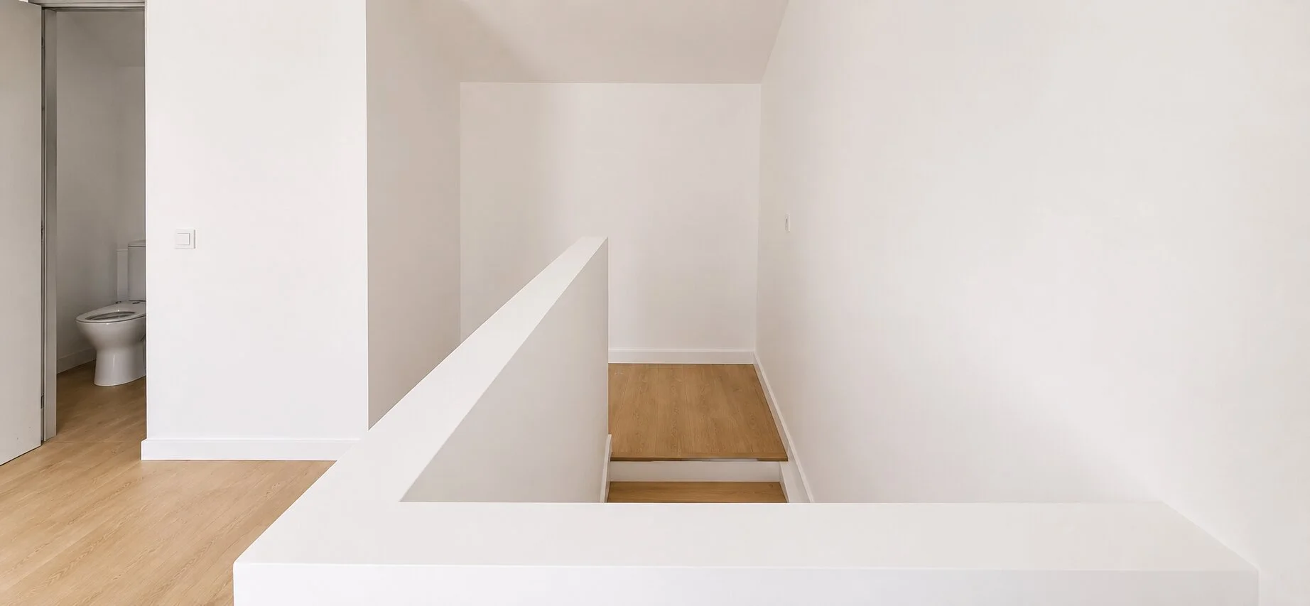 Minimal white interior and oak staircase detail in the renovated house in Cebolais de Cima