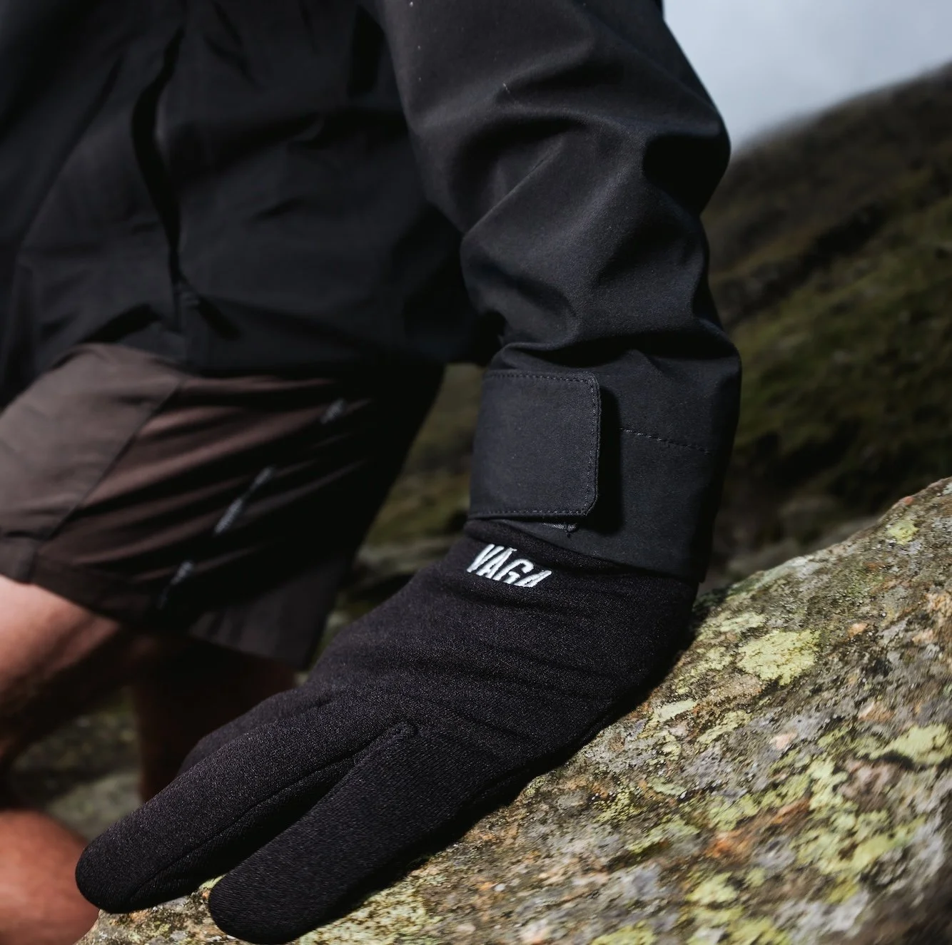 Male runner wearing the VÅGA Endurance Running Glove, placing hand upon rock.