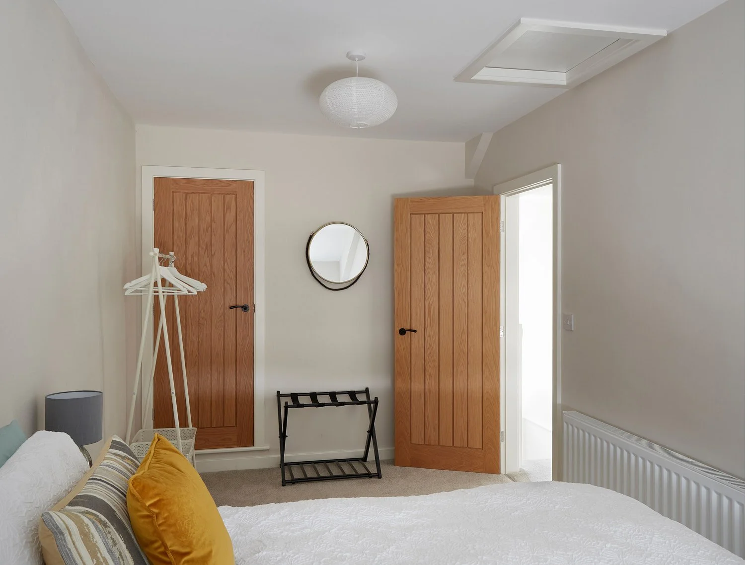 minimal bedroom design with kingsize bed, cushions and open hanging space for clothes