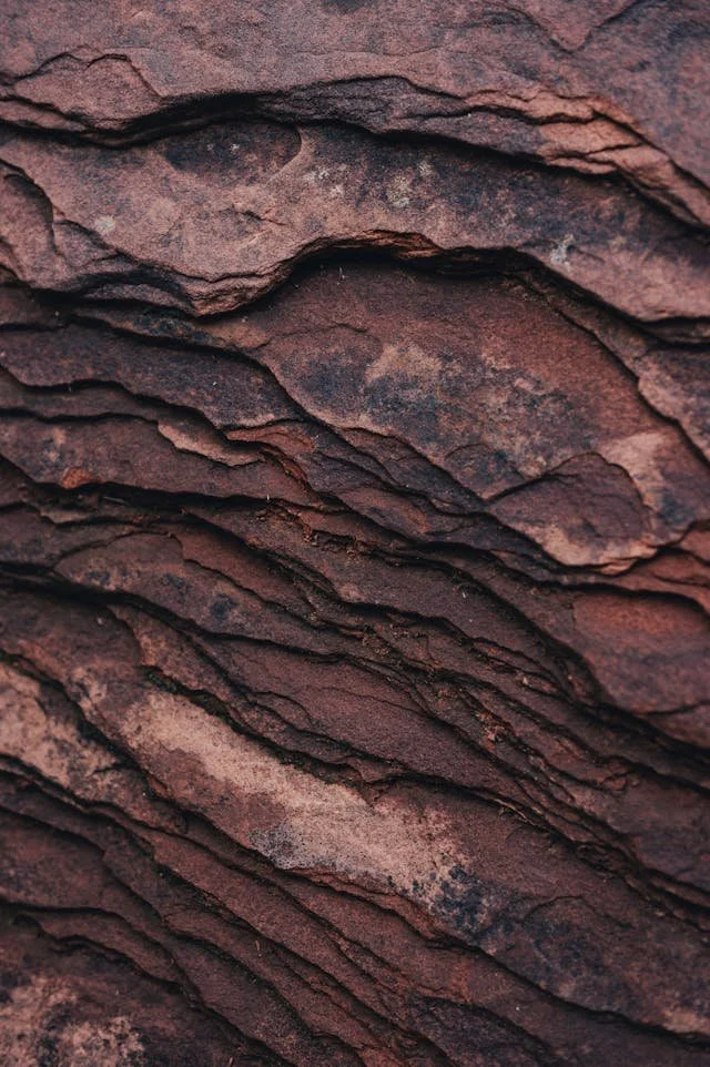 Close-up of layered red and brown rocks or clay with textured, uneven surfaces.