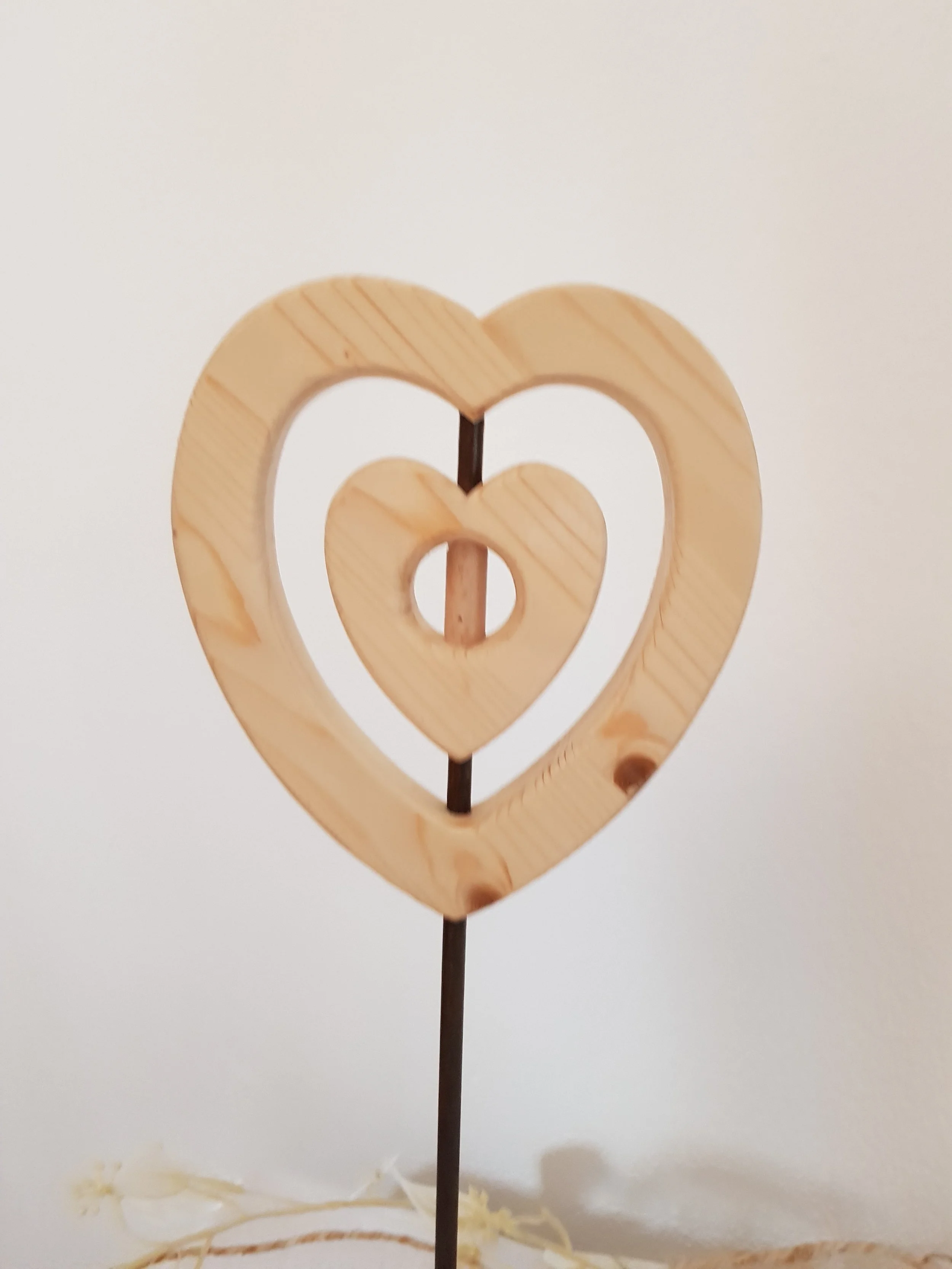 Holzherzdeko auf einem Metallstab gegen weißen Hintergrund.