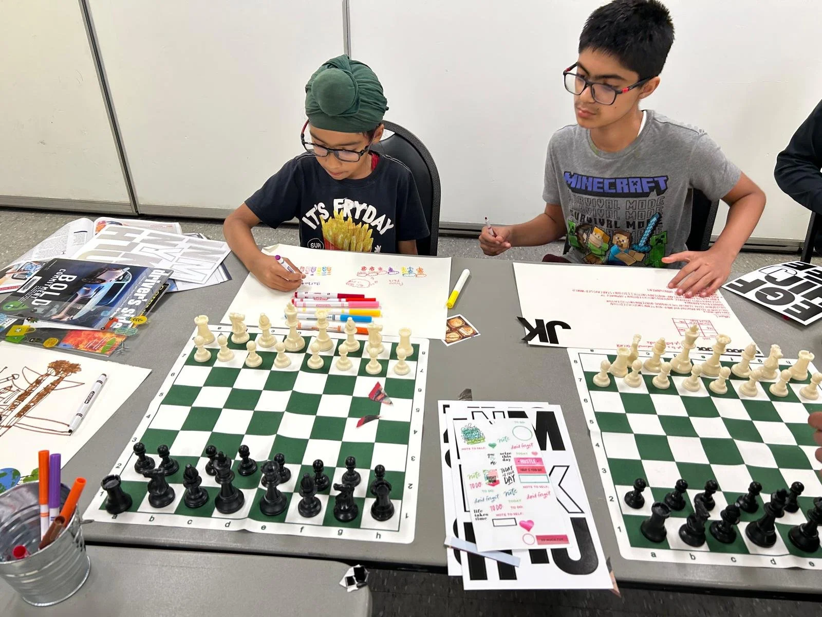Youth participants drawing and playing chess during an Enroute 2 Success community workshop.