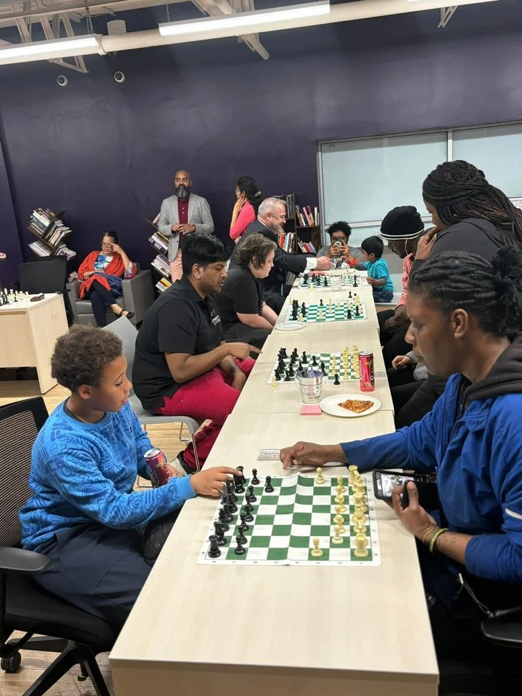  Children and adults playing in a chess tournament hosted by EnRoute 2 Success. 