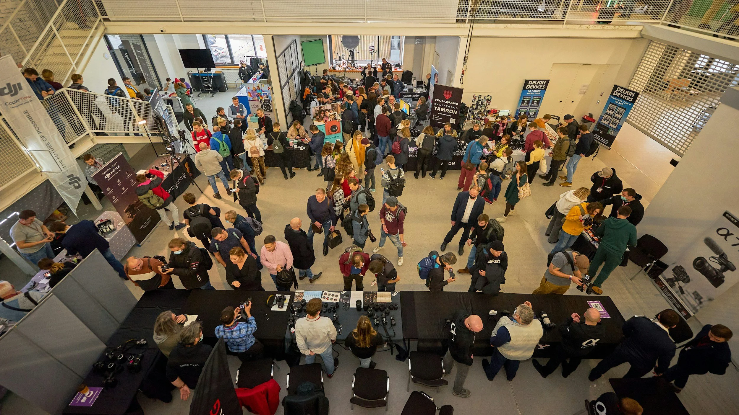 Overhead view of a busy career expo with attendees exploring exhibitor booths, viewing displays, and speaking with representatives.