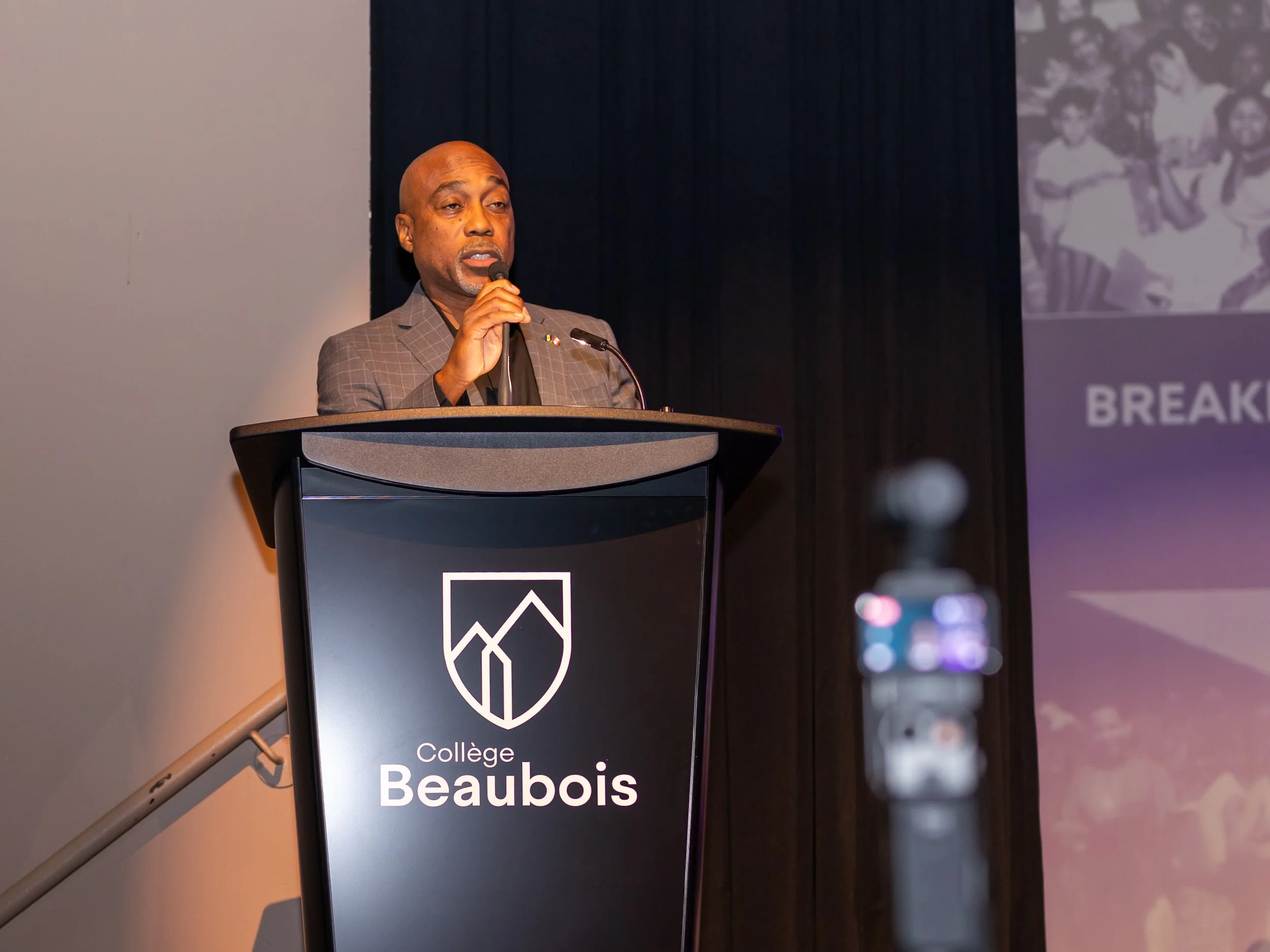 Speaker at podium at Collège Beaubois during Breaking Barriers: The Story of Gloria Baylis event in Montreal