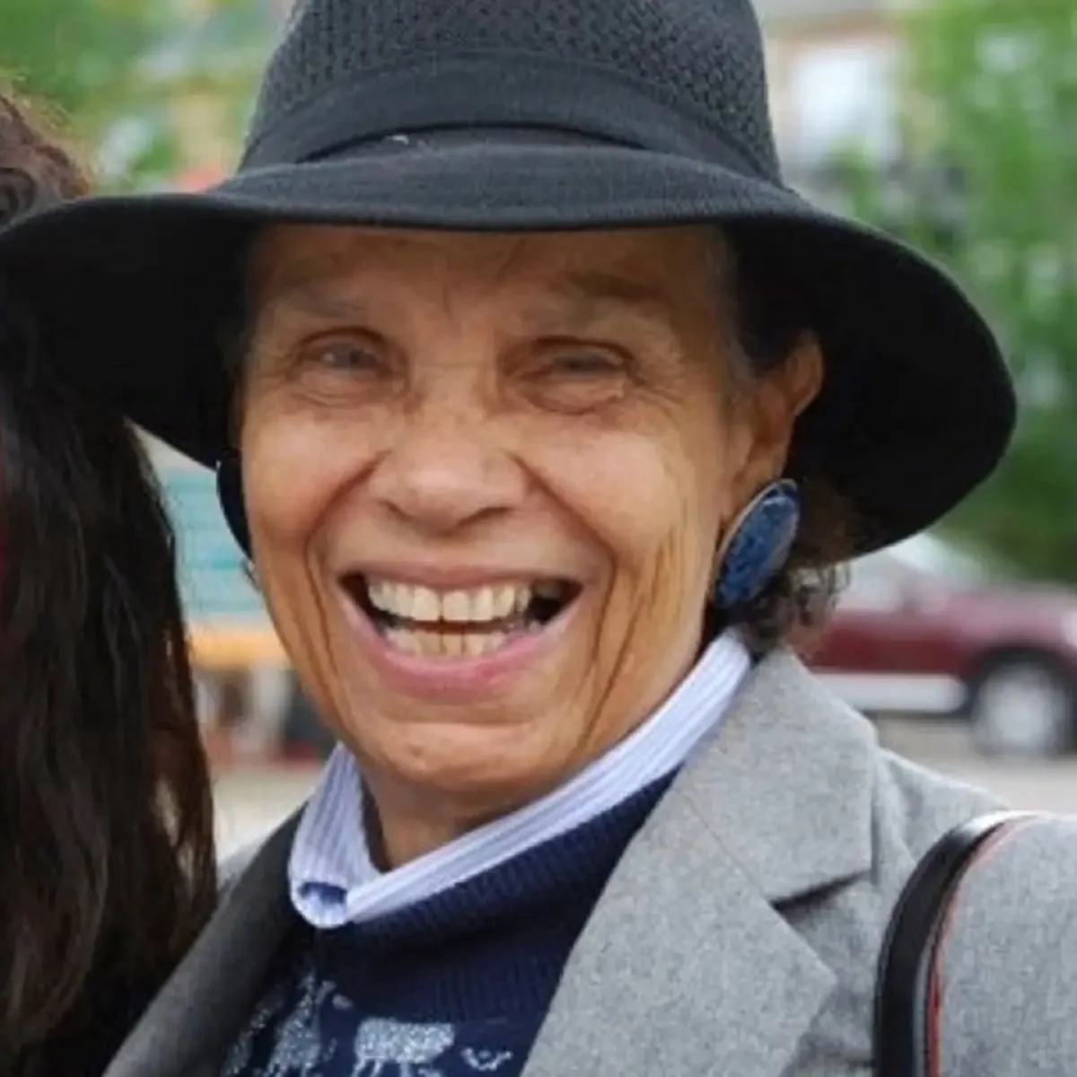 Portrait of Gloria Baylis later in life wearing a black hat and smiling