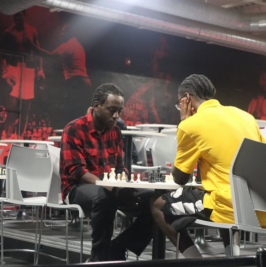 Young adults playing competitive chess during an EnRoute 2 Success community chess event