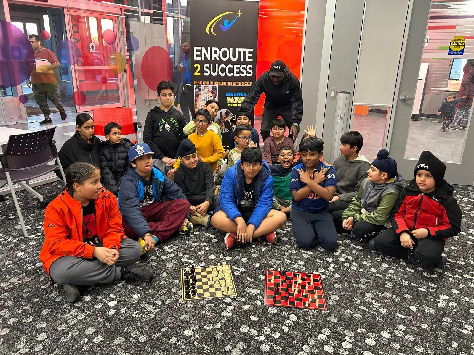Youth participants gathered around chess boards during an EnRoute 2 Success chess session