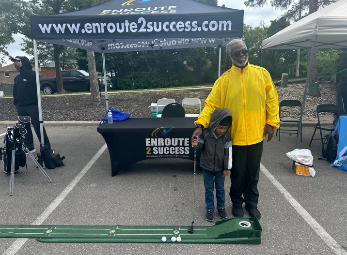 A golf instructor guides youth participants on a putting mat during an EnRoute 2 Success golf lesson at a community event.