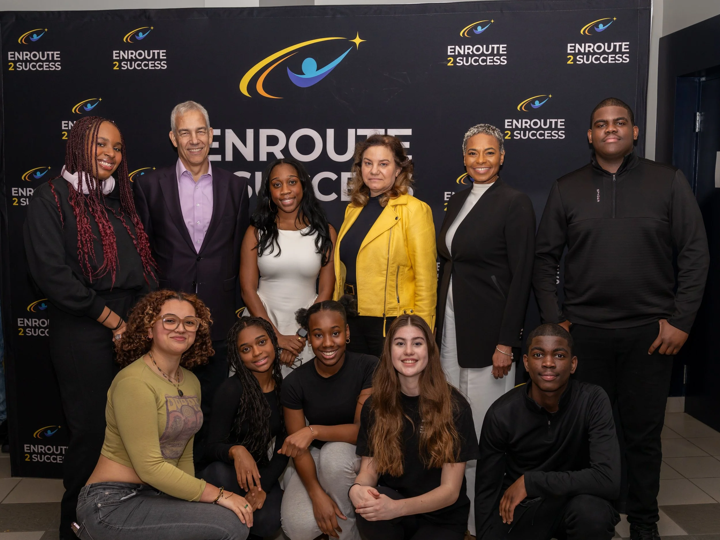 Youth performers and organizers posing in front of EnRoute 2 Success backdrop after Breaking Barriers event
