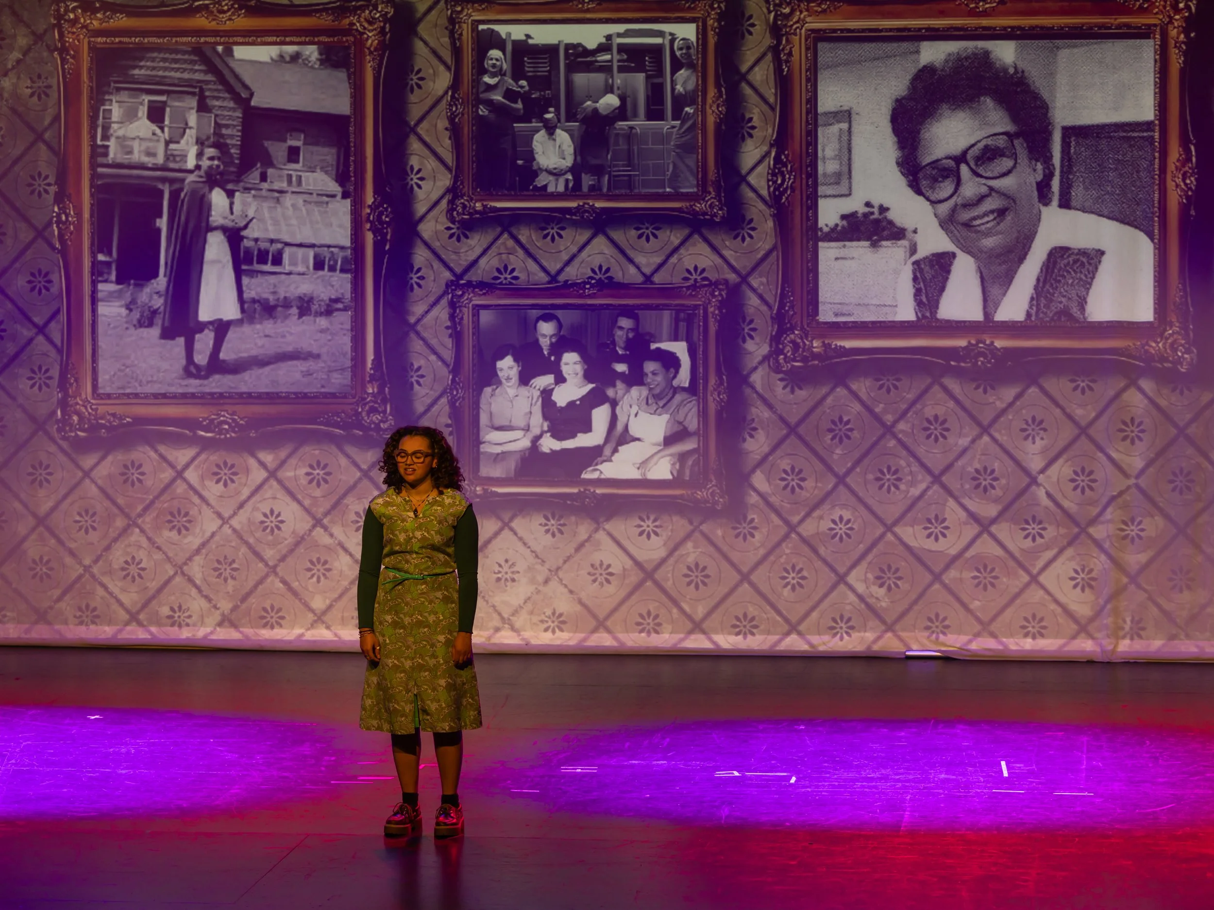 Youth performer on stage during Breaking Barriers: The Story of Gloria Baylis with historic photos projected behind