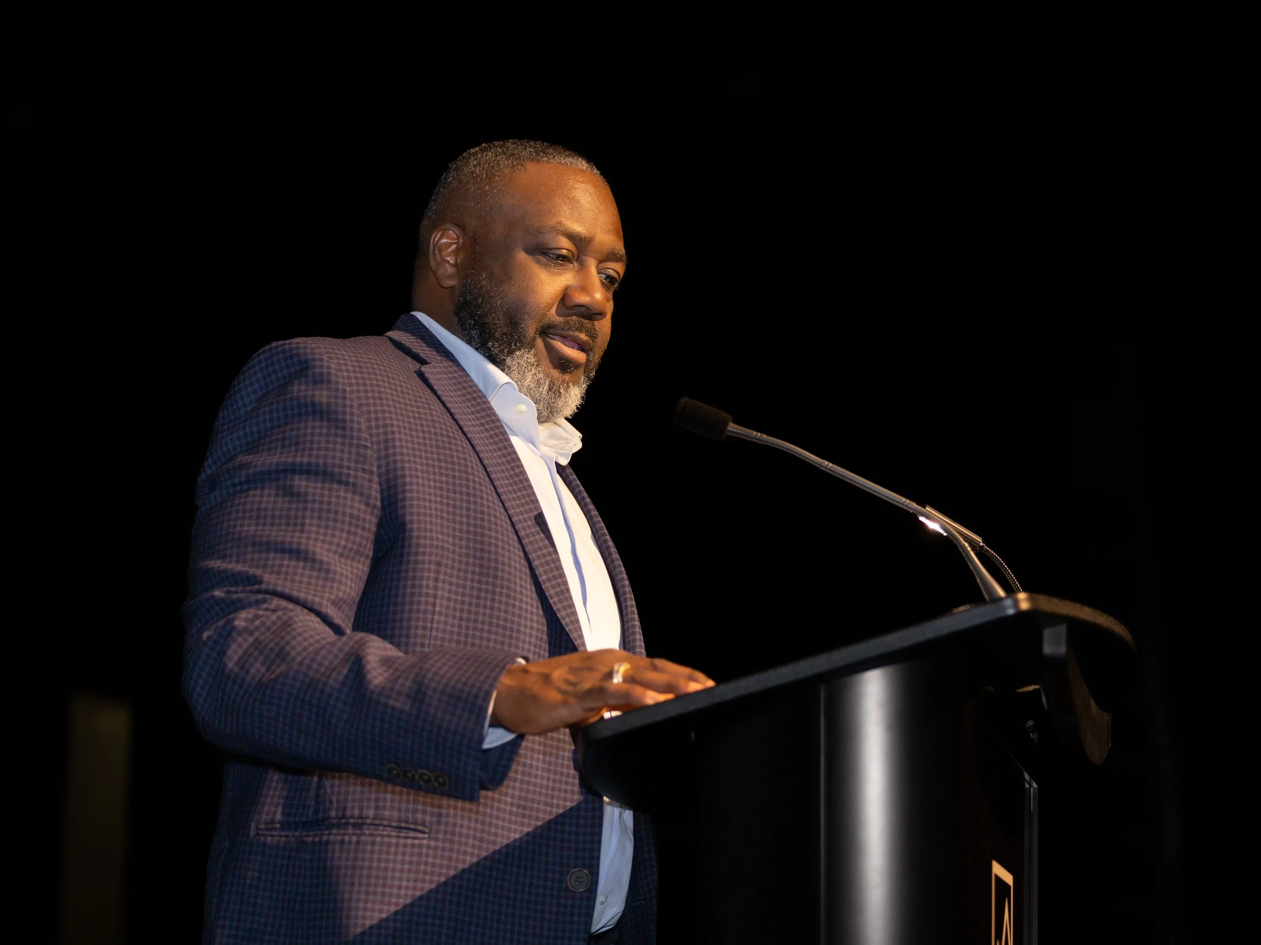 Speaker addressing audience at podium during Breaking Barriers: The Story of Gloria Baylis event