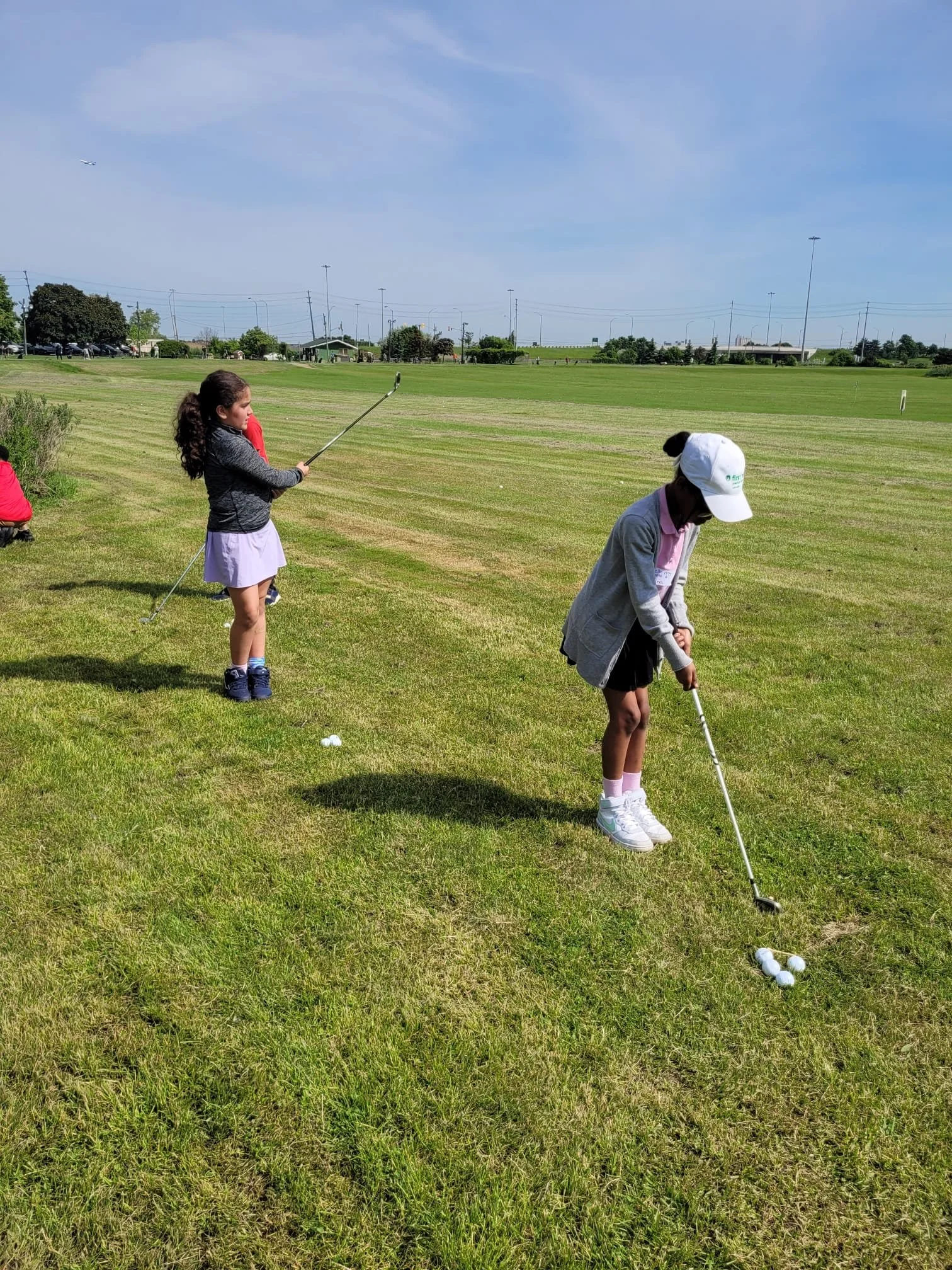 Youth participants practicing golf swings during an Enroute 2 Success golf lesson on a driving range.