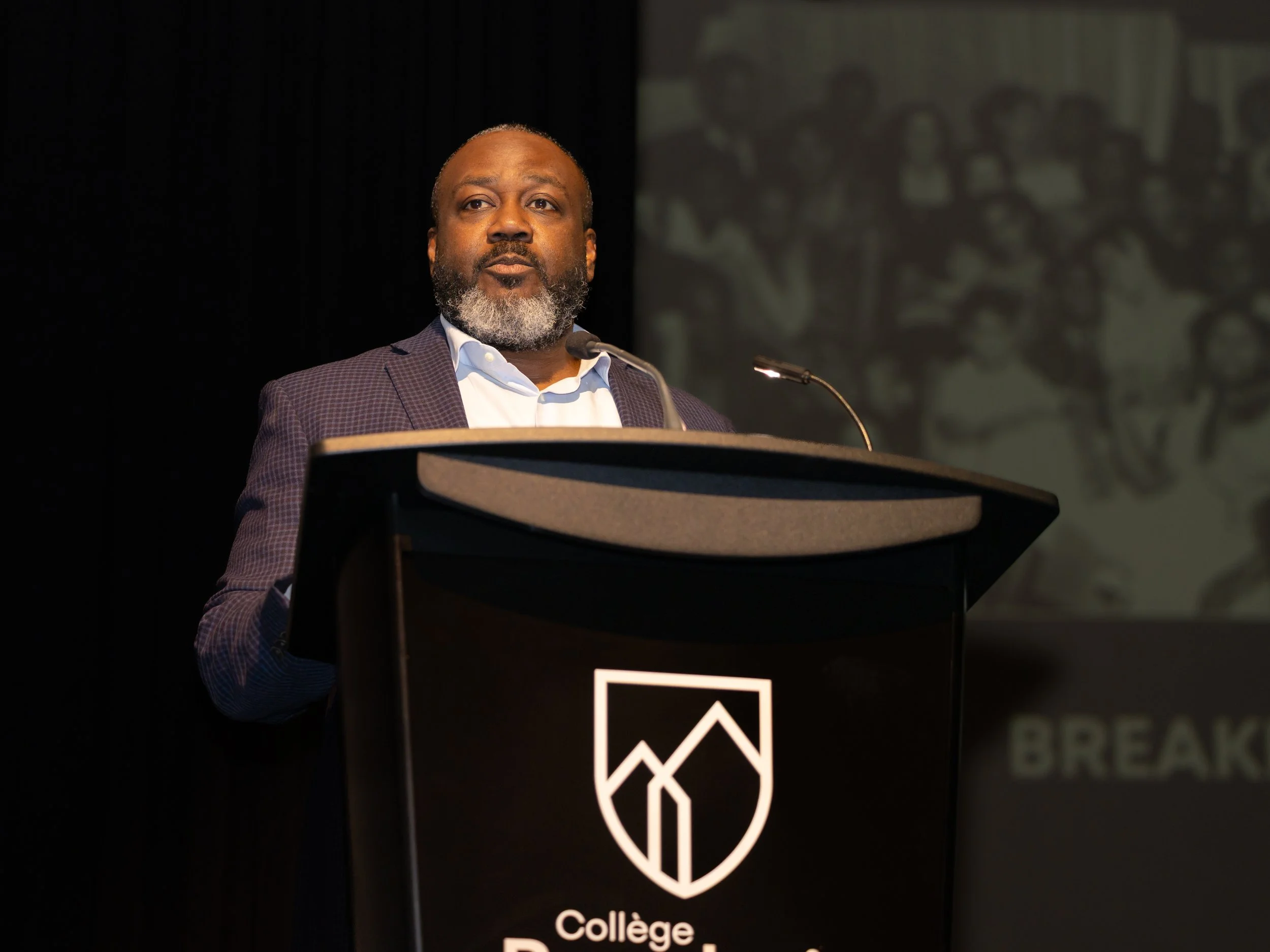 Speaker presenting at podium at Collège Beaubois during the Breaking Barriers event