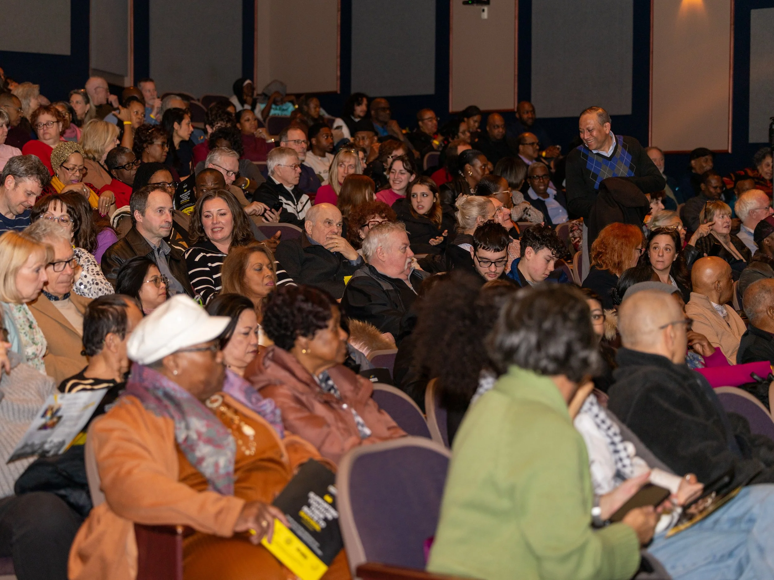 Audience members seated in a theatre attending an Enroute 2 Success community event and stage production.
