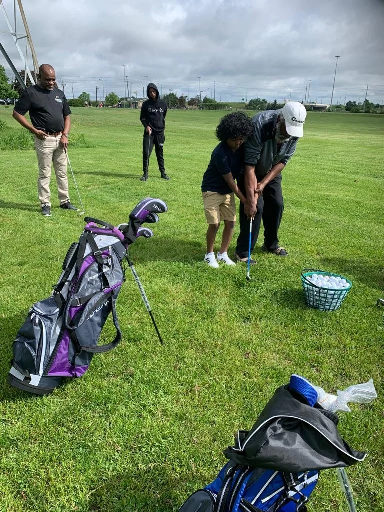 Coach helping a youth participant practice a golf swing during an EnRoute 2 Success golf lesson