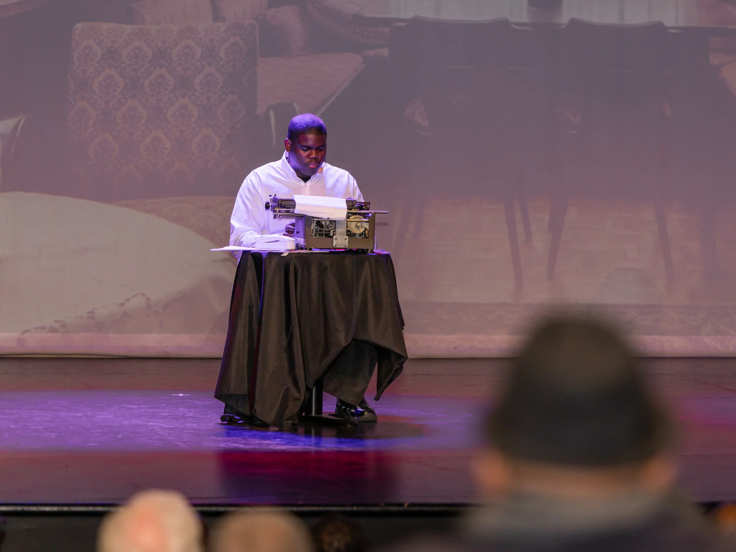 Performer using a typewriter on stage during Breaking Barriers: The Story of Gloria Baylis play