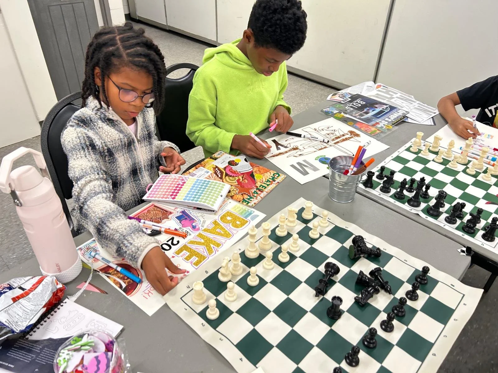 Youth participants drawing and playing chess during an Enroute 2 Success community learning program.