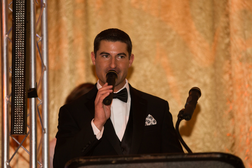 Trey Morris in a tuxedo speaking into a microphone at an event.