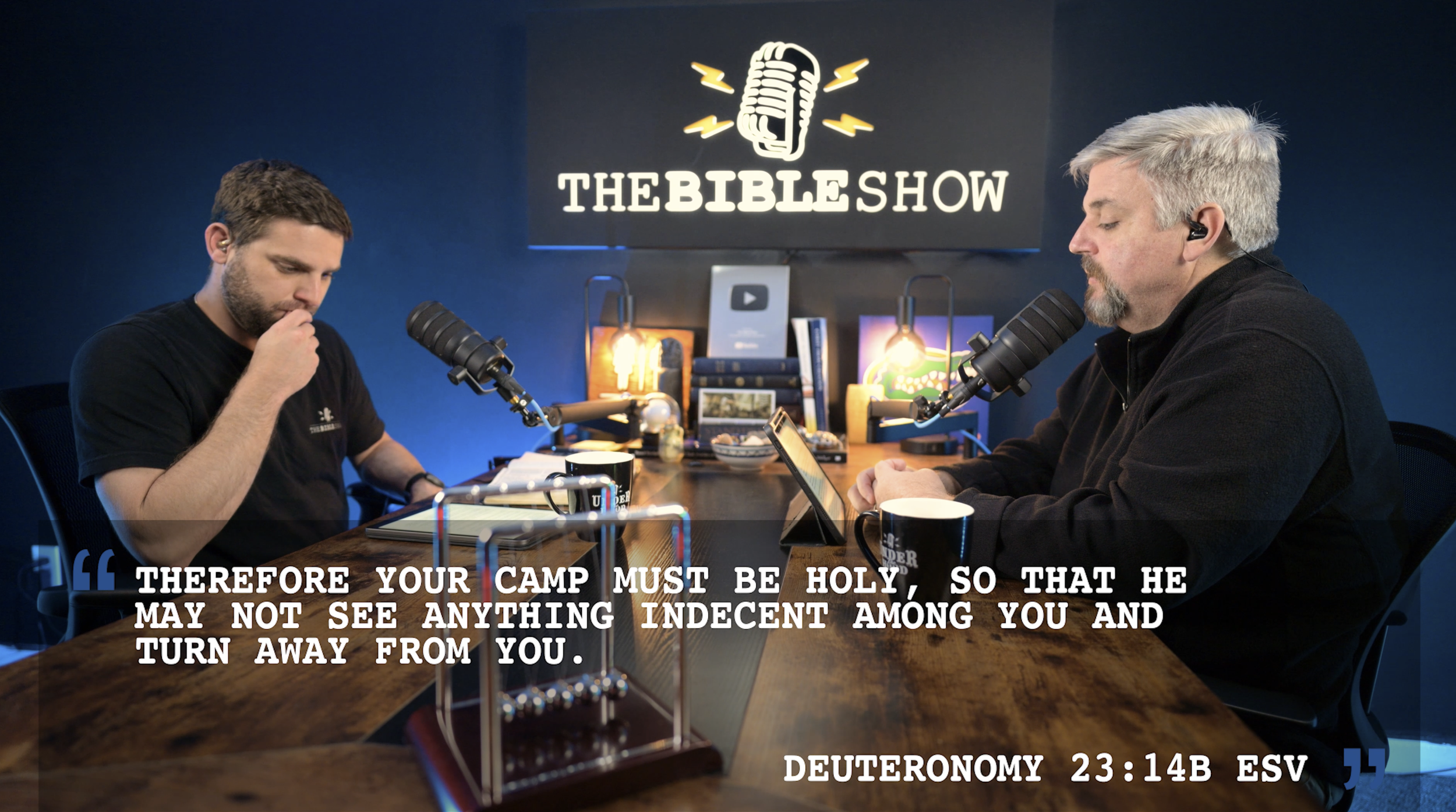 The Bible Show hosts record a video podcast with on-screen scripture text graphics highlighting Deuteronomy 23:14.