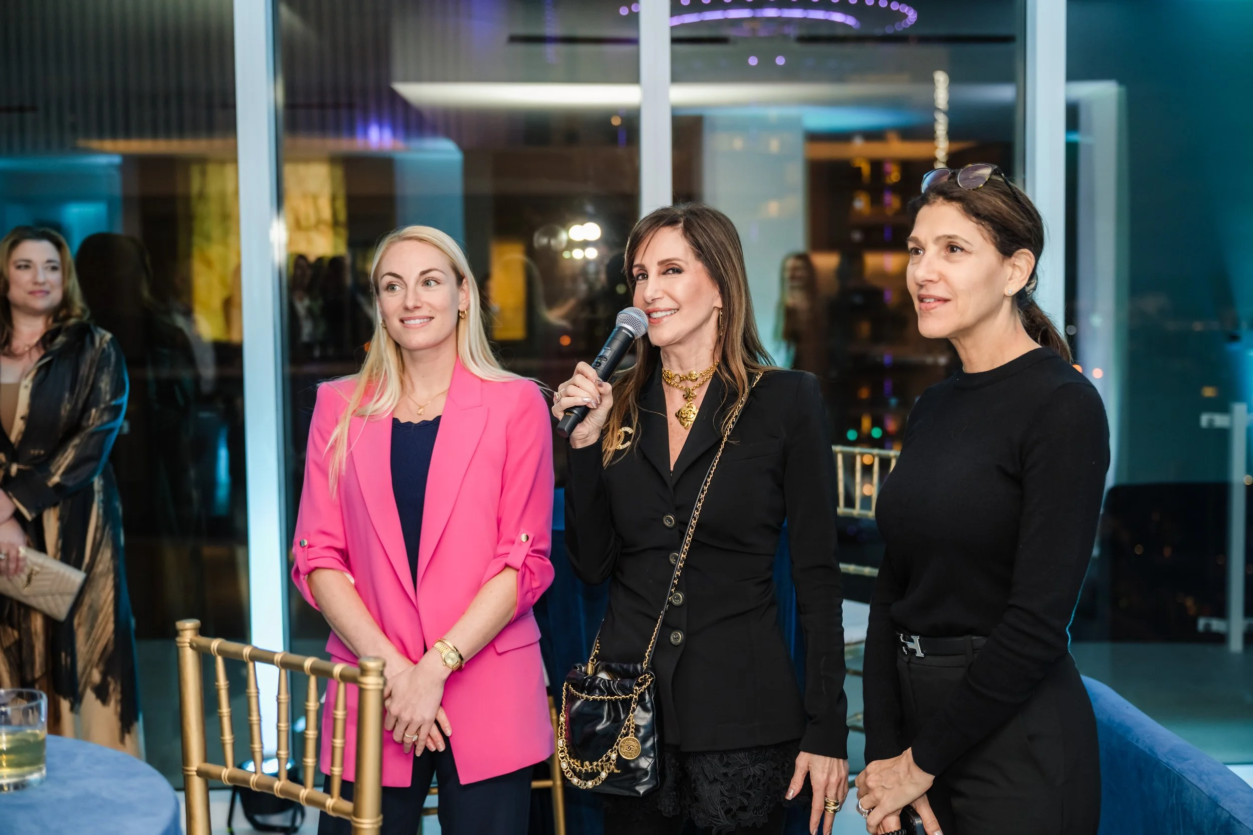 Woman speaking into a microphone with two colleagues at a real estate event presentation at Pier Sixty-Six Fort Lauderdale