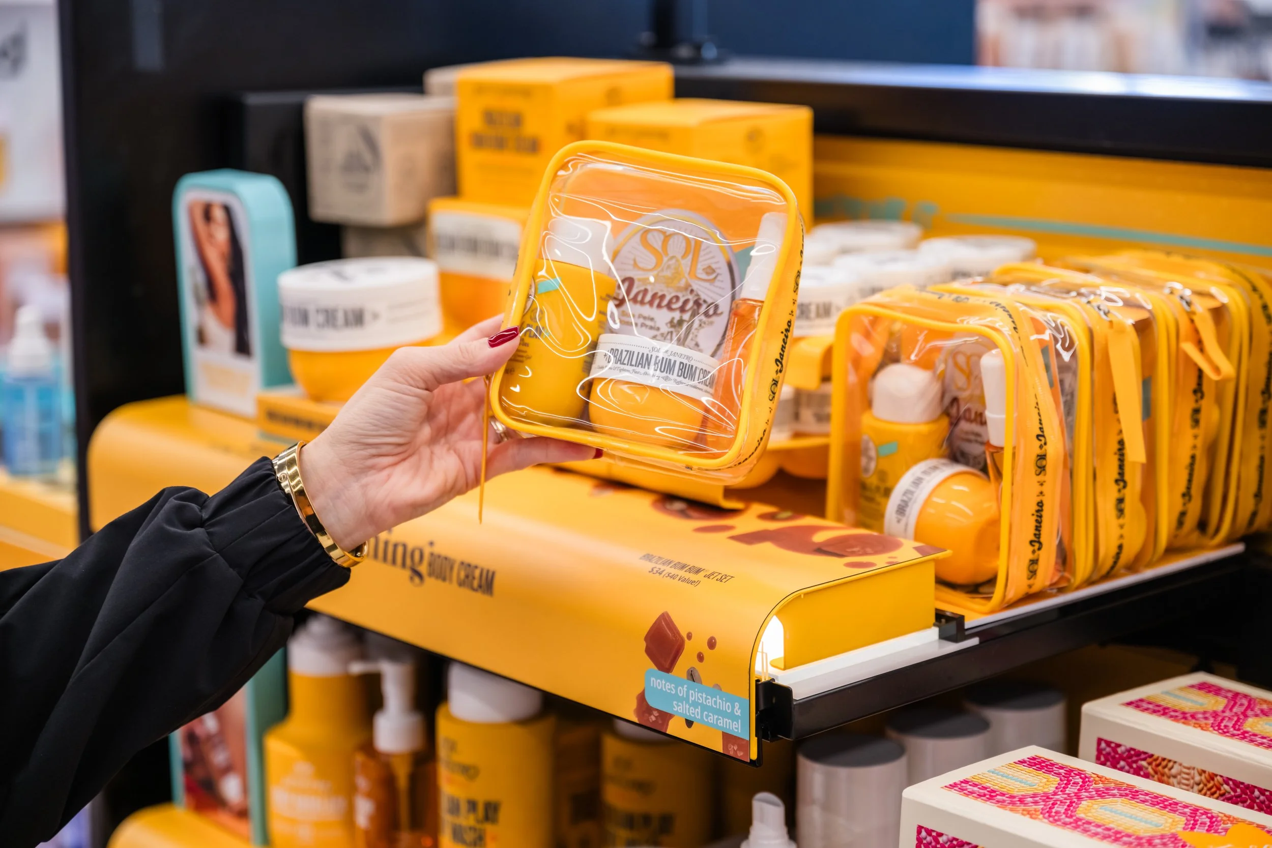 Person holding a yellow coconut oil container in a store aisle of skincare products.