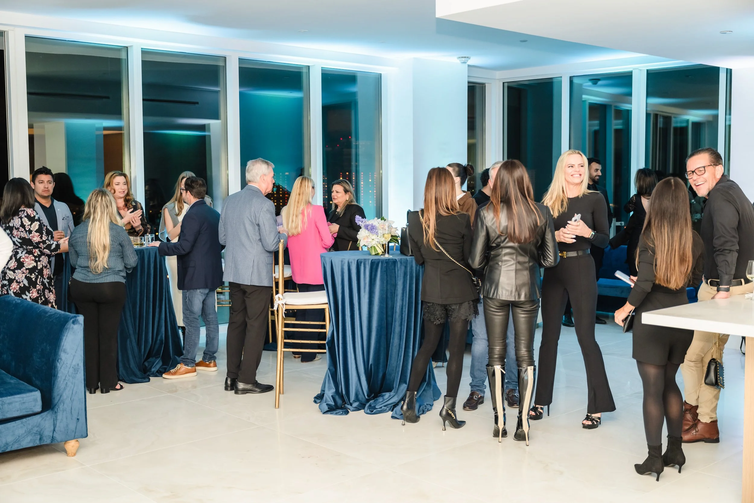Guests mingling at cocktail tables inside a modern event space with floor-to-ceiling windows at a real estate networking event at Pier Sixty-Six Fort Lauderdale