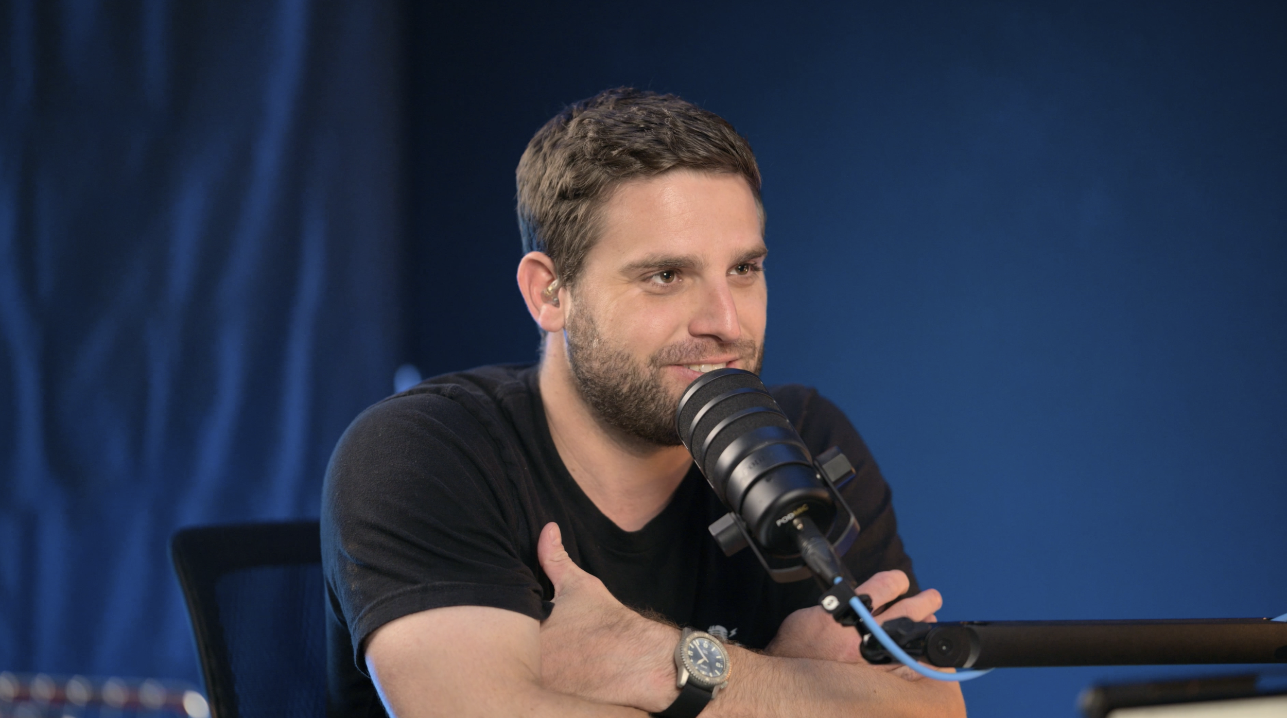 A Bible Show host speaks into a studio microphone during a video podcast episode about the historical background of the Gospel of Matthew.